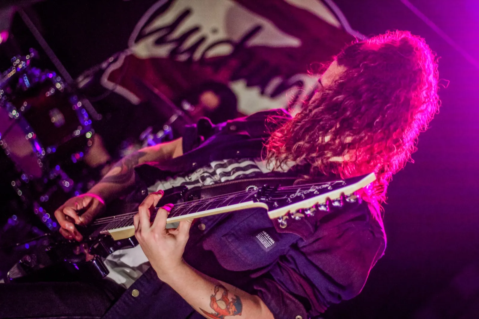 Guitarra en vivo de Midnight Z con luces magenta en una convención